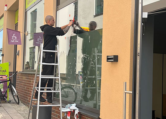 Ein Mitarbeiter von Baden Dienstleistungen reinigt die Fenster eines Geschäftes