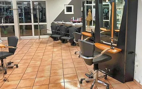 Friseursalon mit mehreren Friseurstühlen, Spiegeln und Waschbecken, gefliestem Boden.