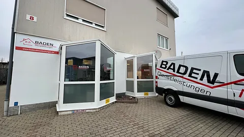 Eingang zu einem Gebäude mit dem Schild 'Baden Dienstleistungen' und einem Lieferwagen mit dem gleichen Logo.